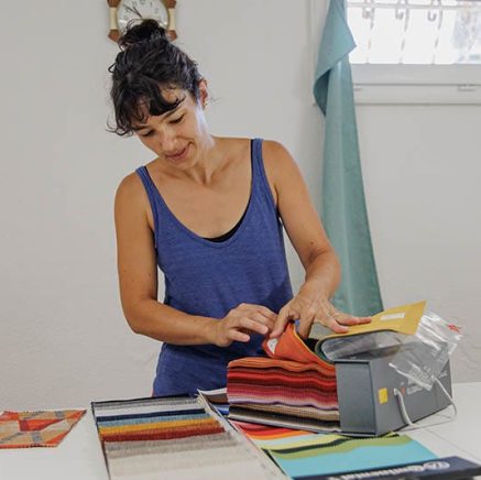 L'artisane en train de choisir une couleur de velours sur une grosse liasse d'échantillons