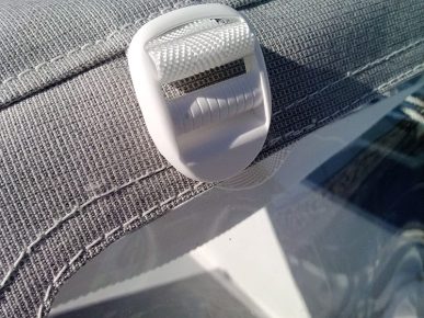 Détail d'une capote de voilier. Zoom sur l'attache de la sangle pour remonter le cristal avant
