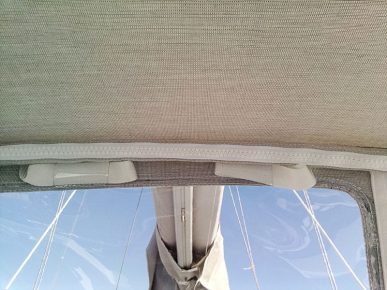 détail intérieur d'une capote de voilier. zip de fourreau blanc et sangles blanches repliées et coincées dans un morceau de cristal