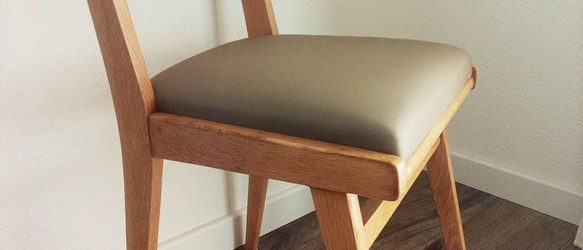 chaise année 50 avec des pieds compas en bois clair. Assise refaite avec un simili effet textile, et dossier en tissu Casal à pois multicolore sur fond écru