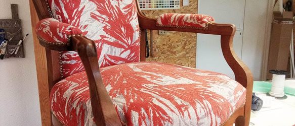 fauteuil voltaire refait avec un tissu feuillage de la maison Casal motif orange en velours avec un fond écru finition clous de tapissier bois chêne moyen