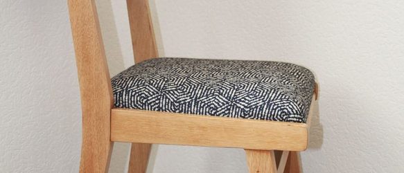 chaise vintage années 50. Pieds compas et bois clair. dossier revêtu d'un tissu orange et assise avec jacquard géométrique filaire bleu marine sur fond écru