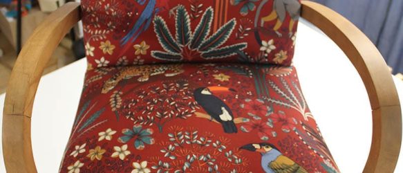fauteuil bridge refait avec un tissu Thévenon rouge aux motifs floraux et animalier